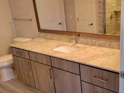 Clean and sanitized bathroom vanity with polished countertop, mirror, and sink area.
