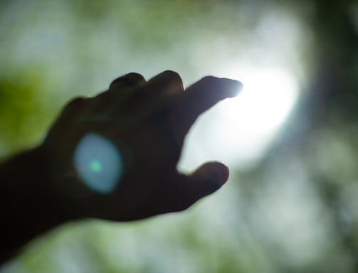 a hand reaching for a light out of focus