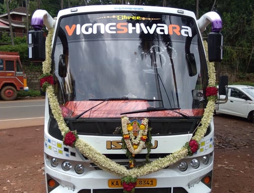 A white color bus with name and decorated by flowers.