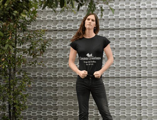 a woman in a black shirt and jeans standing in front of a wall