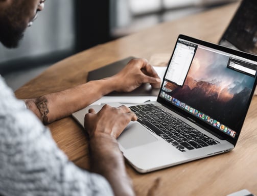 person using macbook pro on white table