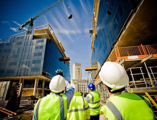 two men in safety vests standing in front of a building