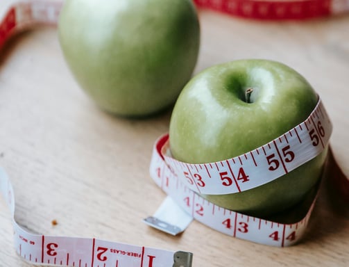 Green apples with a body measuring tape around it 