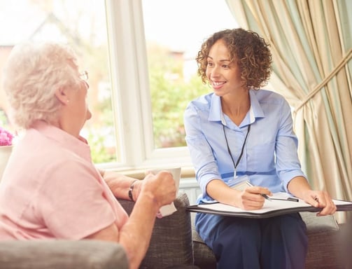 a woman in a blue shirt is sitting on a couch doing a care assessment