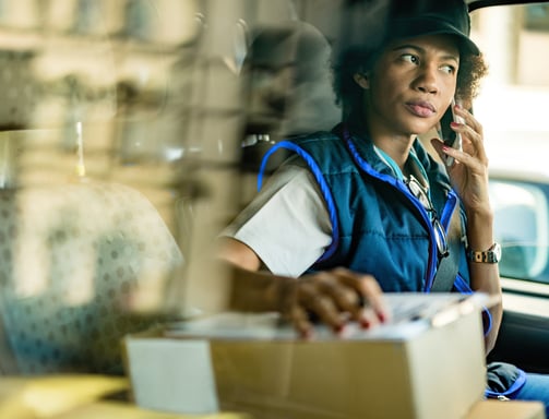 a woman in a blue vest and hat talking on the phone