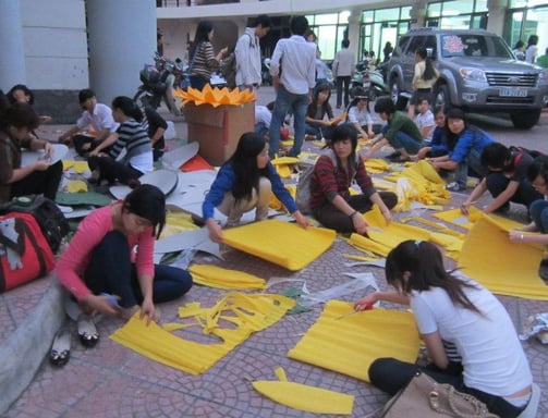 a group of people sitting on the ground with yellow paper