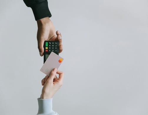 Person holding a credit card while making a payment with a card reader.
