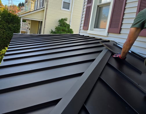 Roofing professional performing emergency metal roof repair after storm damage