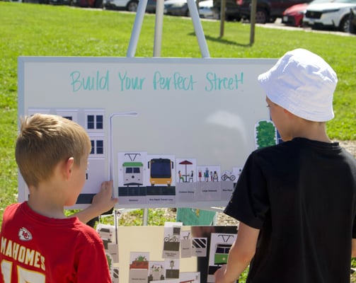 Two children at a whiteboard activity titled "Build Your Perfect Street!"