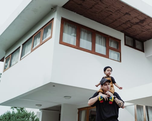 a happy father and child standing in front of a luxury house