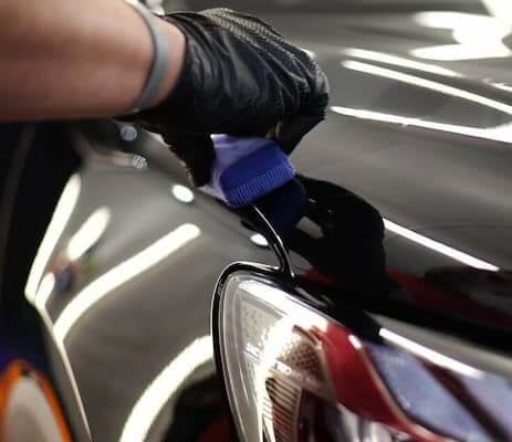 Technician restoring headlight clarity during professional detailing service.