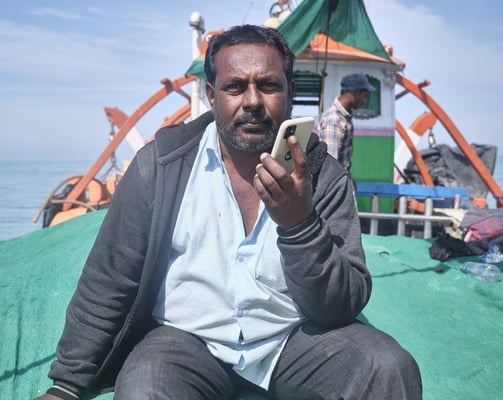 a man sitting on a boat with a cell phone