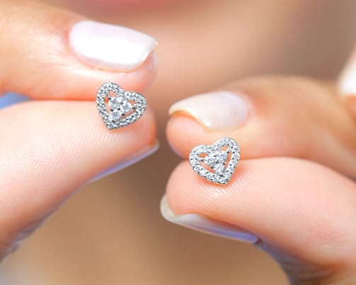 a woman's hand holding a pair of diamond earrings