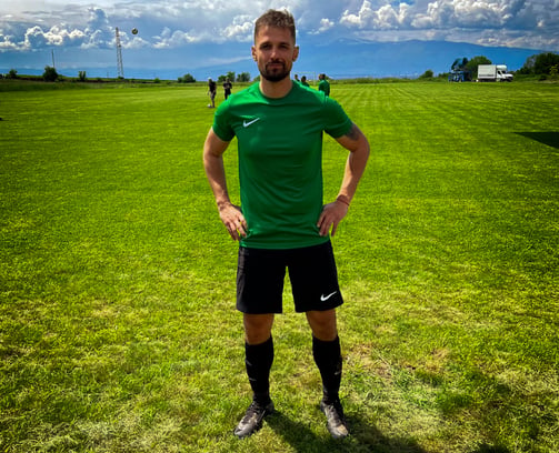 a man in a green shirt and black shorts standing in a field