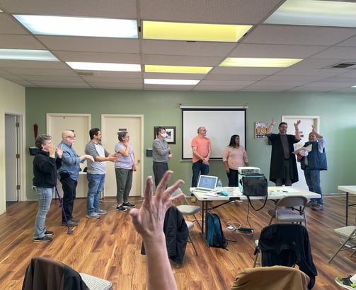 Hand raised in center of photo with people lined up in the background
