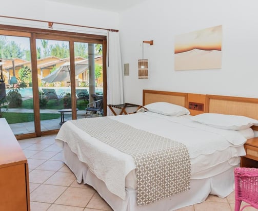 quarto com cama, luminarias e vista para o jardim