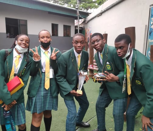 a group of youth holding a trophy and robot