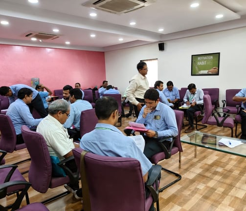 a man in a white shirt is standing in front of a room full of people