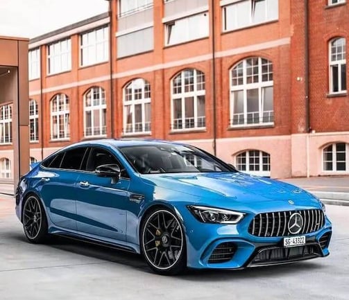 Blue luxury sedan parked in front of a modern brick building, showcasing professional auto detailing