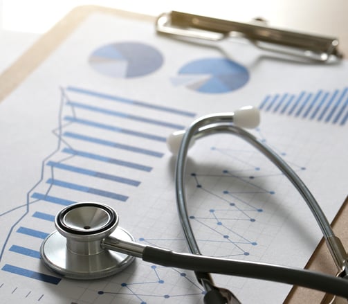 A stethoscope on top of a report with graphs on a clipboard