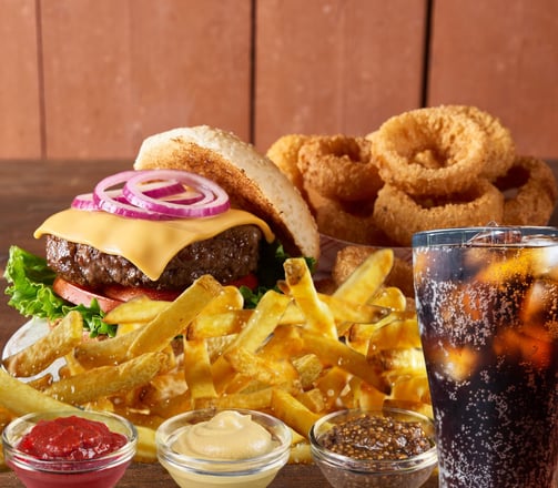 a burger with fries onion rings and a soft drink