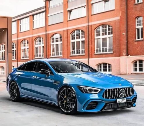 Coche deportivo azul estacionado frente a un edificio de ladrillo durante un servicio de detallado d