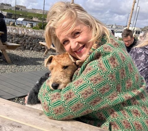 smiling blonde woman cuddling a dog
