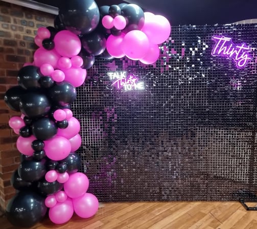 Black shimmer wall with pink neon and black balloon garland, pink Thirty neon for Kristen's 30th birthday.