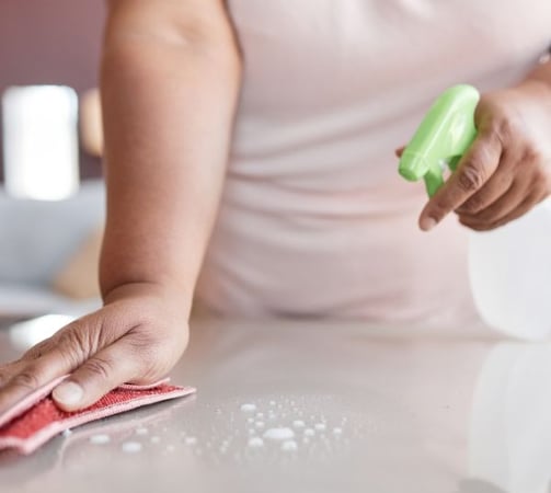 a woman cleaning a counter top with a sponge pad
