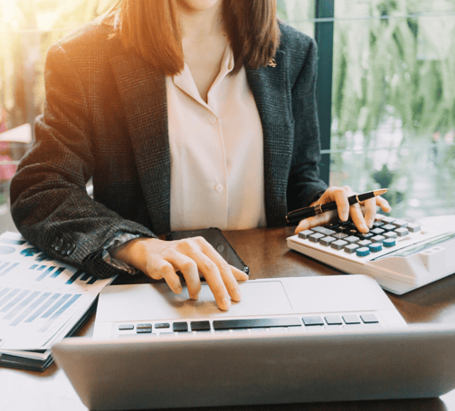 an accountant sitting at a desk with a calculator and laptop reviewing management reports