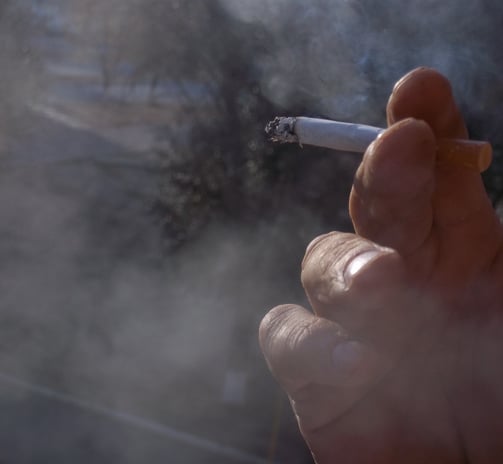 main qui tient une cigarette allumée