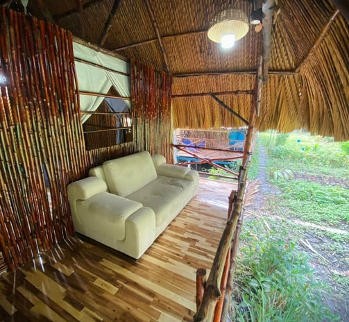 Cozy room with a comfortable sofa on the porch, perfect for relaxing in a rustic bamboo hut.
