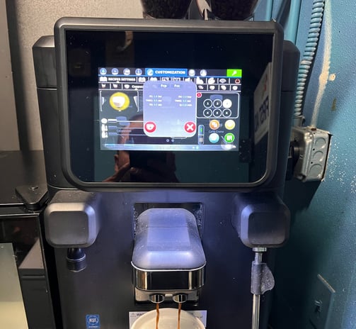 La Cimbali super-automatic espresso machine preparing cappuccino with touchscreen interface