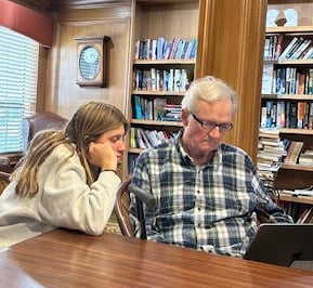 teen girl helping older man with his computer