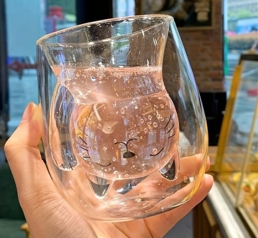 a person holding a cate shaped double wall glass
