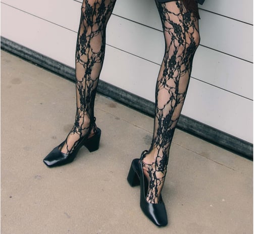 a woman in a black dress and black shoes
