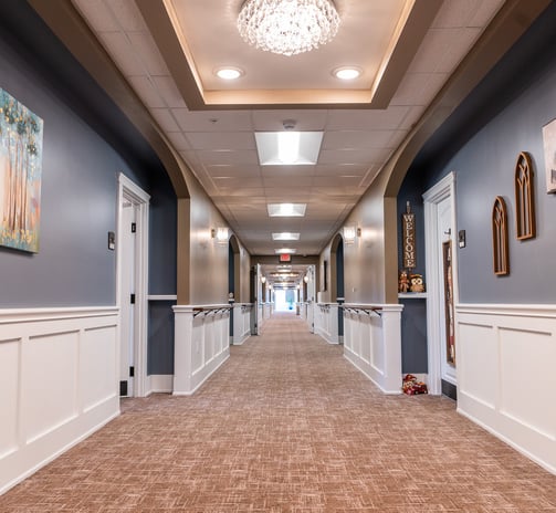 a hallway with a carpeted floor and a chandelier