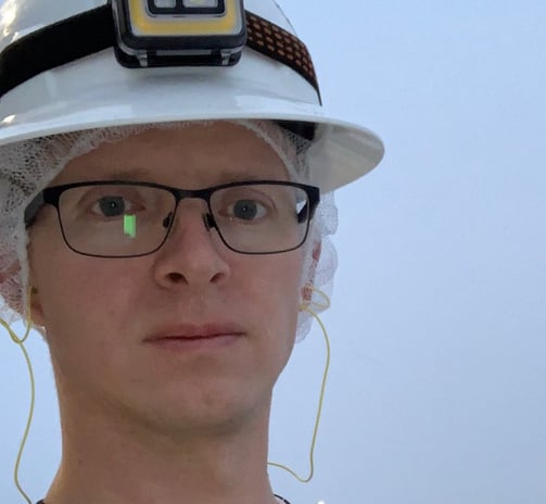 Tomkins dressed in a safety vest and hard hat standing outside on a snowy day. 