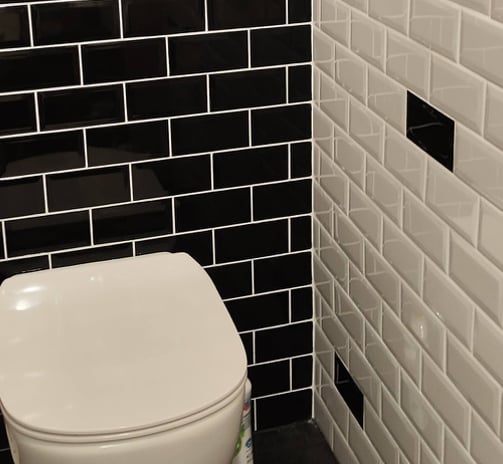 WC suspendu, revêtu avec faïences métro noire et blanches
