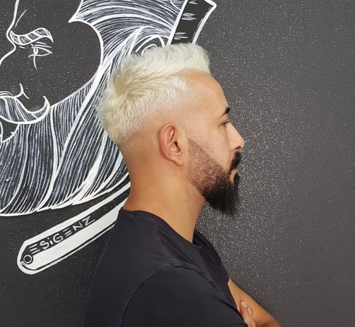 Taglio sfumato con capelli decolorati e barba definita.