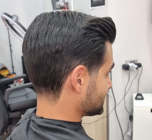 Taglio classico con sfumatura bassa e ciuffo pettinato all’indietro