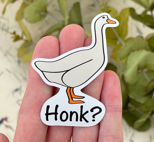 a person holding a sticker with a goose on it