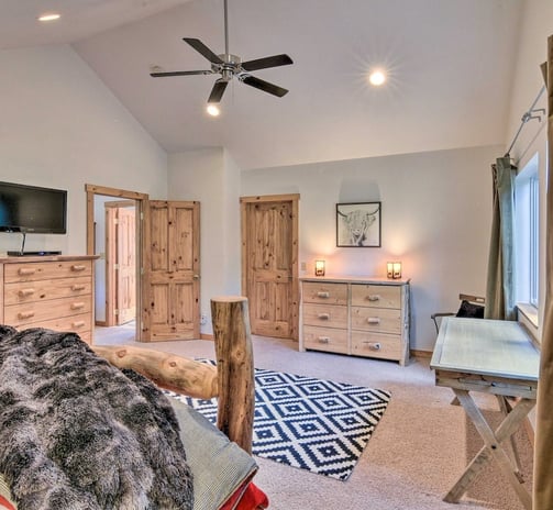 Master bedroom with wooden dressers, ceiling fan, and black and white rug.