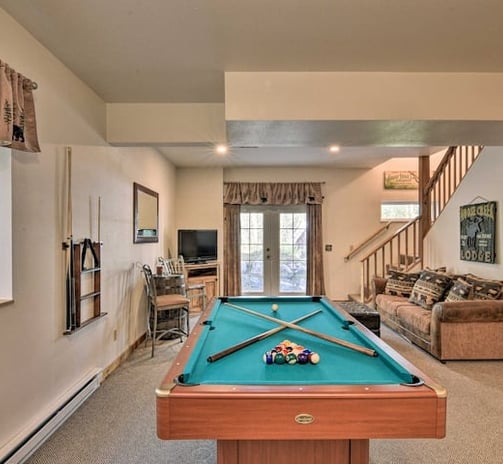 Cozy game room at Moose Creek Lodge featuring a pool table, TV, and lounge area with deck access.
