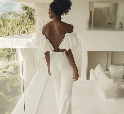 A black woman wearing white with her back to the audience 