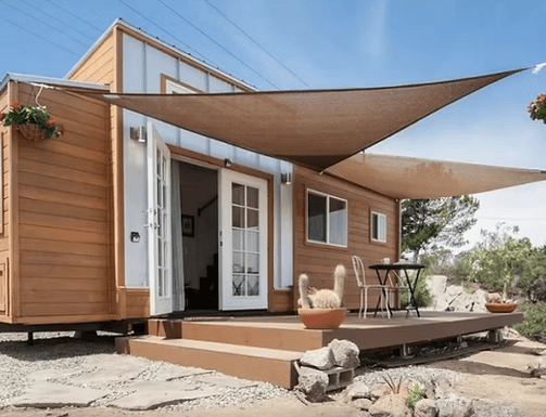 Tiny home pod with deck, shade sail, and outdoor seating