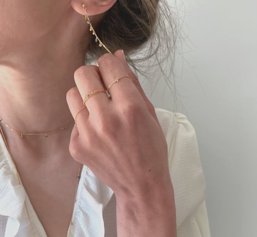 Photo bijoux BYNORA portés. Chaîne d'oreilles, bagues, sautoir et bracelet avec des diamants bruts multicolors
