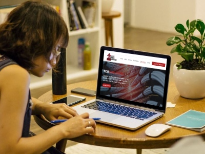 a woman sitting at a table with a laptop and a cell phone