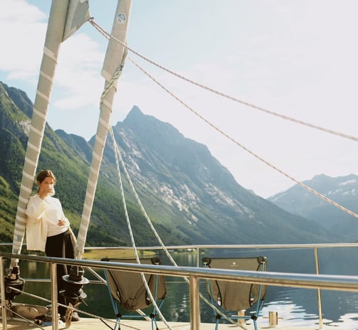 Georgina Amorós on sailboat deck with scenic mountain backdrop during summer sailing in Lofoten