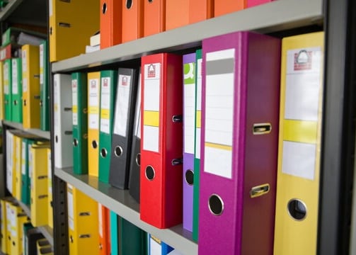 a bunch of folders on a shelf in a library